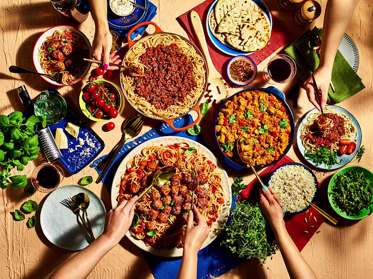 Vegetarian pizza, made with vegetarian cheese, peppers, tomato and pesto, served on a platter board.