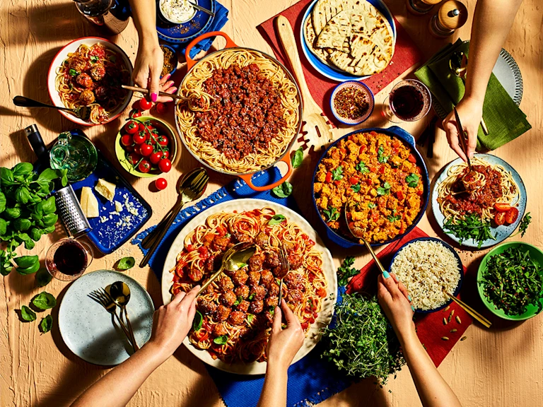 Vegetarian pizza, made with vegetarian cheese, peppers, tomato and pesto, served on a platter board.