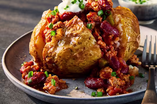 A jacket potato sliced to show the vegetarian chilli made using Quorn Vegetarian Mince.