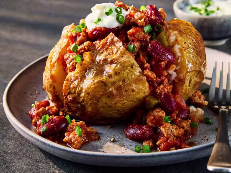 A jacket potato sliced to show the vegetarian chilli made using Quorn Vegetarian Mince.