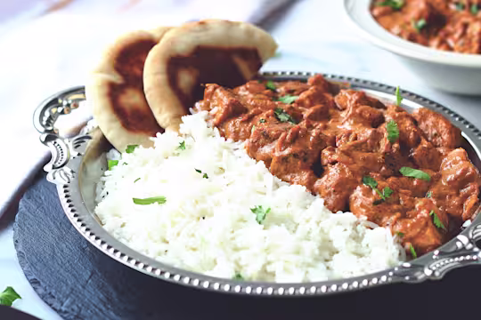 A butter chicken curry made with Quorn Meatless ChiQin Pieces served with a side of rice and naan bread.