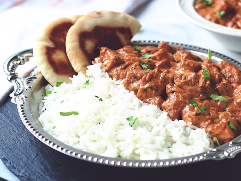 A butter chicken curry made with Quorn Meatless ChiQin Pieces served with a side of rice and naan bread.