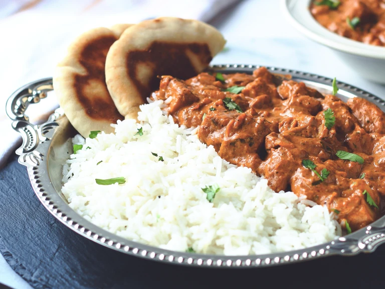 A vegan butter chicken curry made with Quorn Meatless Vegan Pieces served with a side of rice and naan bread.