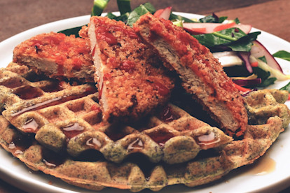 Quorn Meatless Vegan Chipotle Cutlets atop and blue corn waffle topped with syrup with collard green slaw on the side.