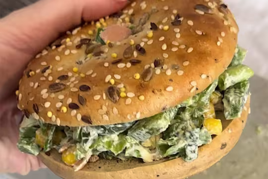 A loaded chopped bagel with Quorn Smoky Ham held to show the filling on the bagel.