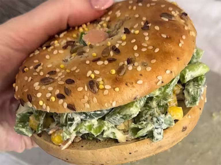 A loaded chopped bagel with Quorn Smoky Ham held to show the filling on the bagel.