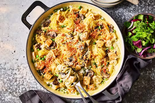 Spaghetti tetrazzini with Quorn Pieces, mushrooms and topped with cheese served in a dish with a side salad.