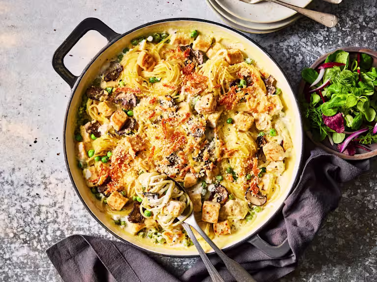 Spaghetti tetrazzini with Quorn Pieces, mushrooms and topped with cheese served in a dish with a side salad.