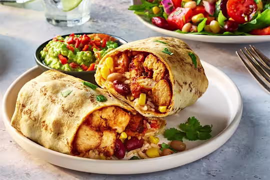 Air fryer vegetarian burrito cut in half to show the filling including Quorn Vegetarian Chicken Pieces, sweetcorn and kidney beans with a side of guacamole.