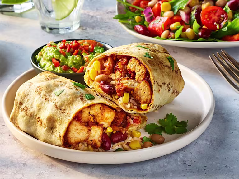 Air fryer vegetarian burrito cut in half to show the filling including Quorn Vegetarian Chicken Pieces, sweetcorn and kidney beans with a side of guacamole.