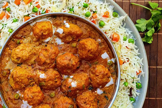 A shahi kofta masala curry made with Quorn Swedish Style Balls in a dish atop a bed of pulao rice.