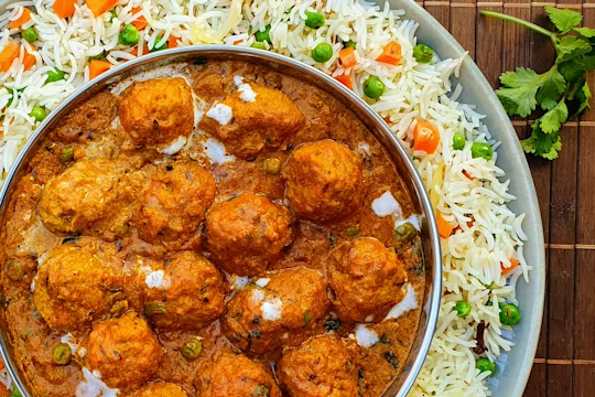 A shahi kofta masala curry made with Quorn Swedish Style Balls in a dish atop a bed of pulao rice.