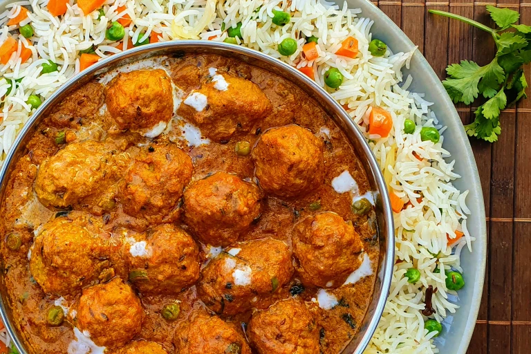 A shahi kofta masala curry made with Quorn Swedish Style Balls in a dish atop a bed of pulao rice.