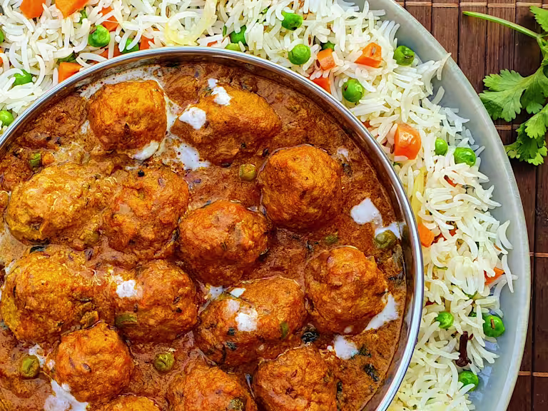 A shahi kofta masala curry made with Quorn Swedish Style Balls in a dish atop a bed of pulao rice.
