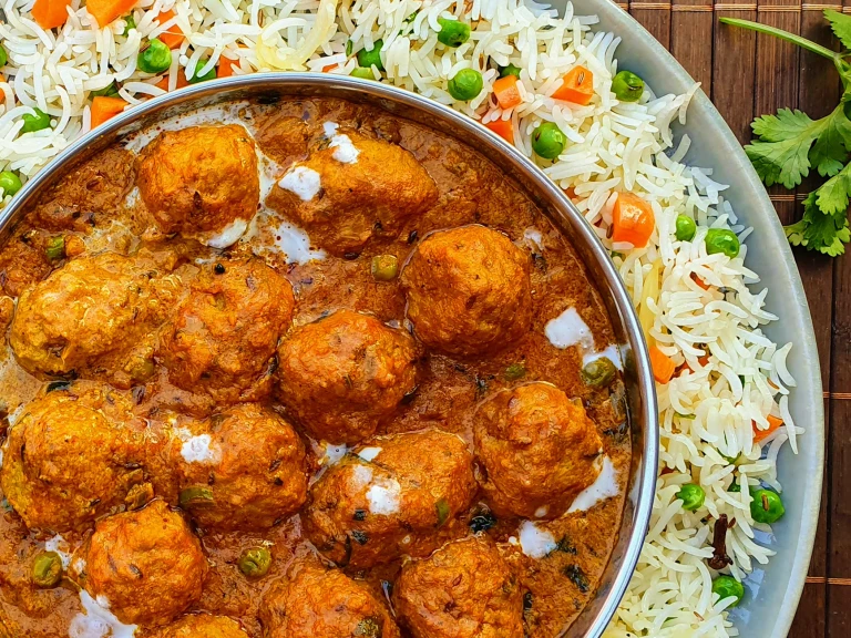 A shahi kofta masala curry made with Quorn Swedish Style Balls in a dish atop a bed of pulao rice.