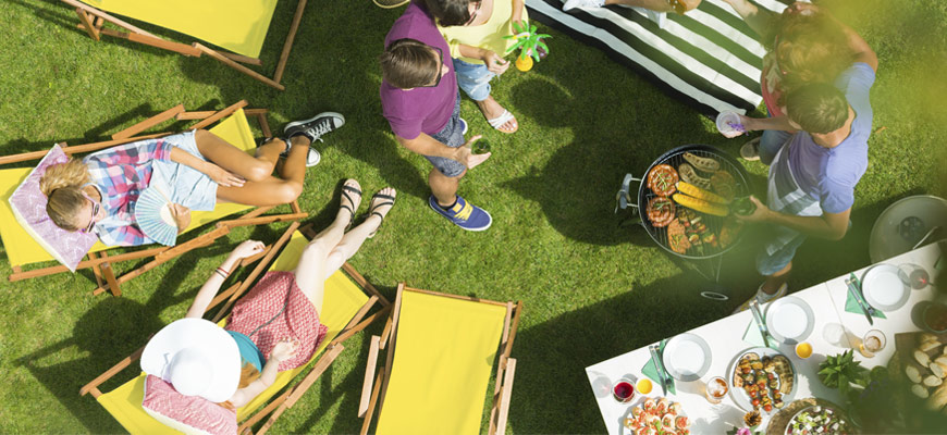 A photo of people cooking corn and meat outside, drinking wine, and having a great time. 