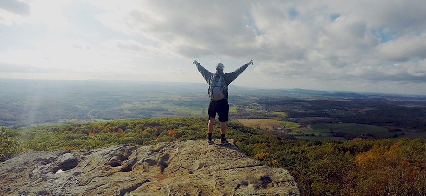 Man standing on a hill yellin and looking free. 