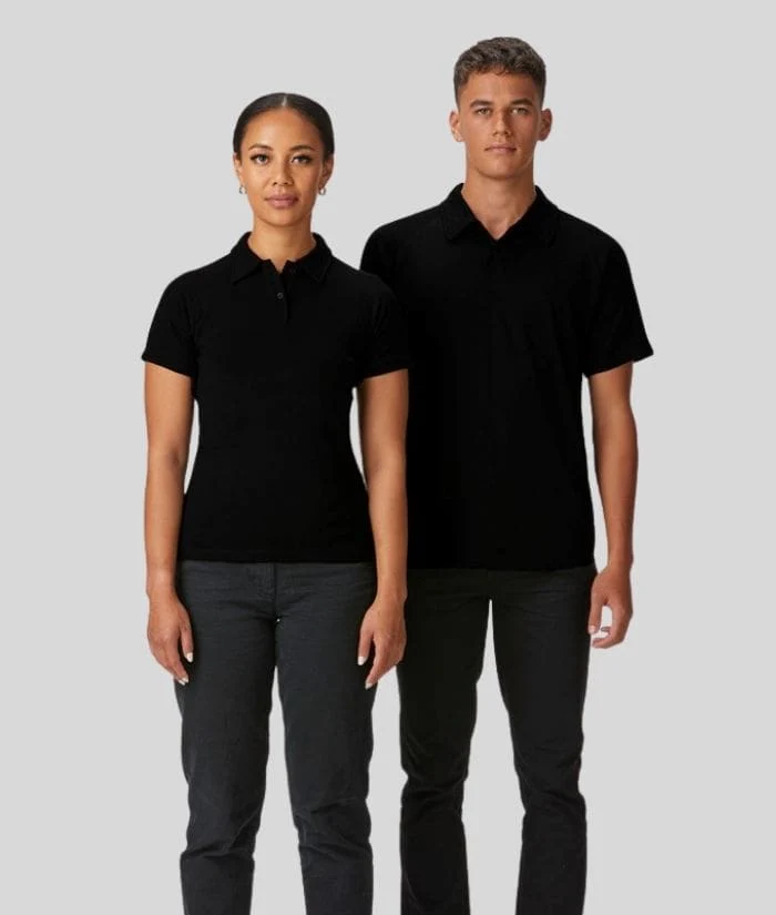 A woman and man stand side by side against a light gray background, both wearing matching black short-sleeved polo shirts with collar details and dark pants, presenting a professional uniform look.