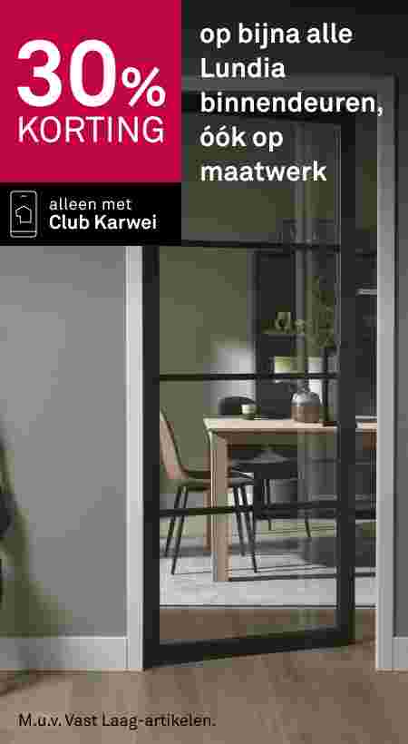 Zwarte glazen binnendeur van Lundia op een kier, met zicht op een eetkamer met houten tafel en stoelen.
