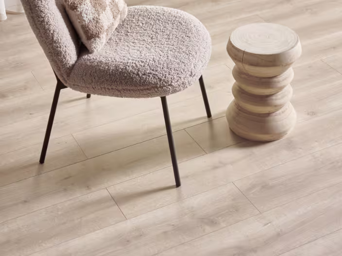 rechte stroken laminaat met een beige teddystoel en een houten bijzettafeltje