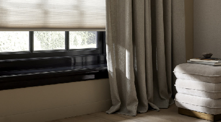 Beige vouwgordijnen hangend voor een kozijn