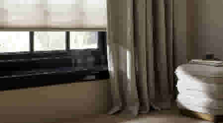 Beige vouwgordijnen hangend voor een kozijn