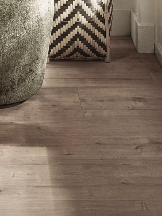 Moderne interieur met houten vloer, decoratieve vaas met gouden textuur en zigzag patroon kussen naast witte trap.