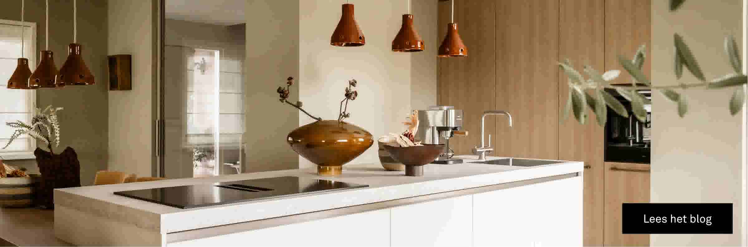 Moderne keuken met wit kookeiland, houten kasten, koperen hanglampen en decoratieve vazen op het aanrecht.
