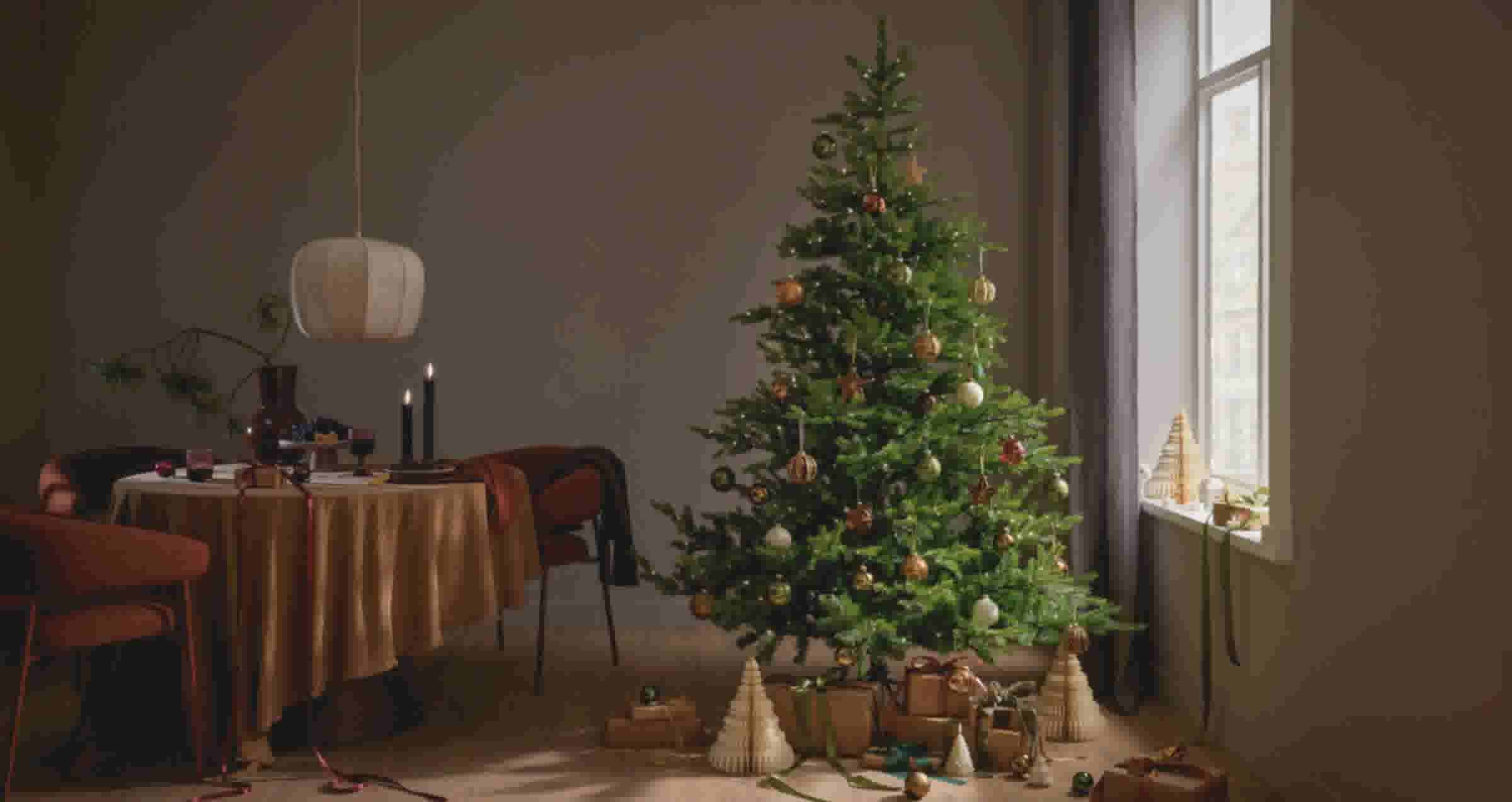 Een sfeervol ingerichte woonkamer met een versierde kerstboom vol gouden en groene ballen, cadeautjes eronder en een gedekte ronde tafel met kaarsen en warme bruintinten.
