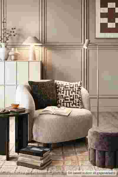 Moderne leeshoek met grijze fauteuil, staande lamp, decoratieve kussens en wandpanelen in neutrale tinten.