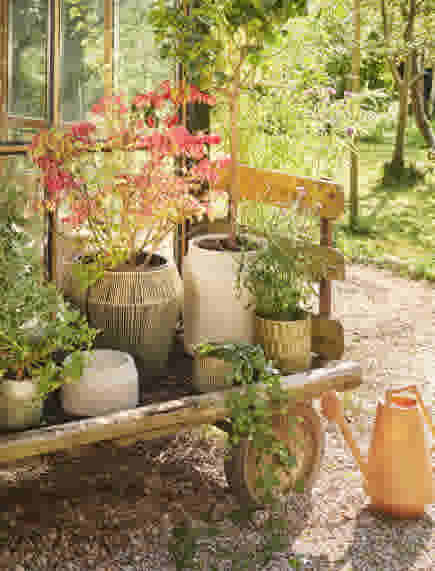Bloempotten op houten karretje in tuin