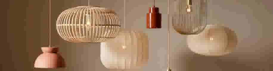 Diverse hangende designlampen in natuurlijke tinten - bamboe, terracotta en papieren armaturen met warme verlichting.