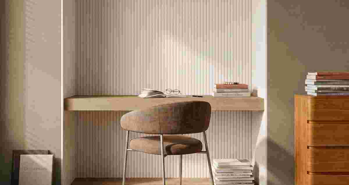 Minimalistische werkhoek met houten bureau, bruine stoel, opengeslagen boek en bril. Stapels boeken en houten ladekast ernaast.
