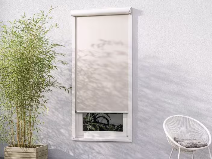 Wit ritsscreen naast bamboe plant in houten bak en een moderne witte stoel met kussen.