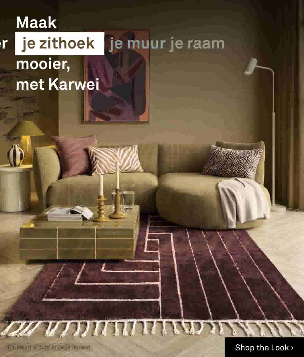 Shop the look: Sfeerbeeld van een olijfgroene loungebank met sierkussens, houten salontafel met kandelaars, voor een kunstwerk en vloerlamp, op een paars-roze patroonkleed.