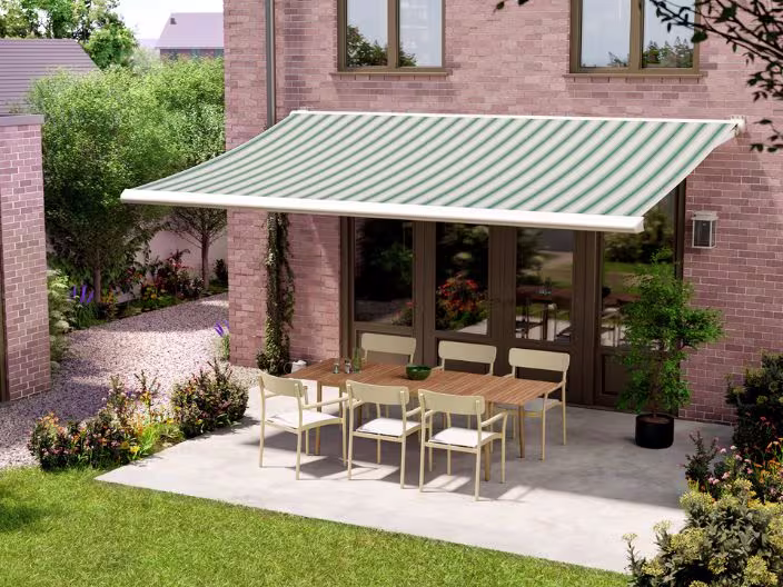 Terras met groen-wit gestreepte zonwering boven een houten tafel met stoelen, naast een bakstenen huis met tuin.