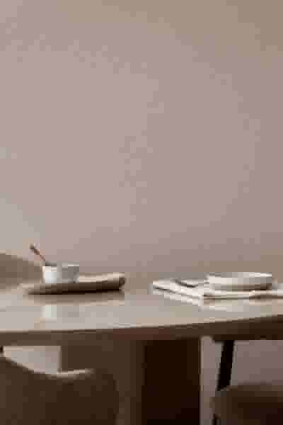 Minimalistisch gedekte tafel, tegen een neutrale beige achtergrond met textielbehang van Le Noir & Blanc.