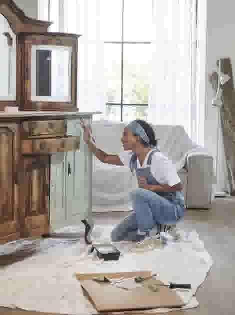 Vrouw die een oude houten kast in de woonkamer mintgroen verft