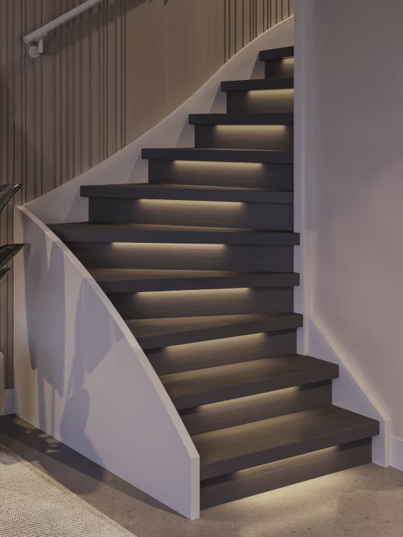 Moderne trap met donkere treden en ingebouwde LED-verlichting onder elke trede, witte wanden en houten lambrisering.