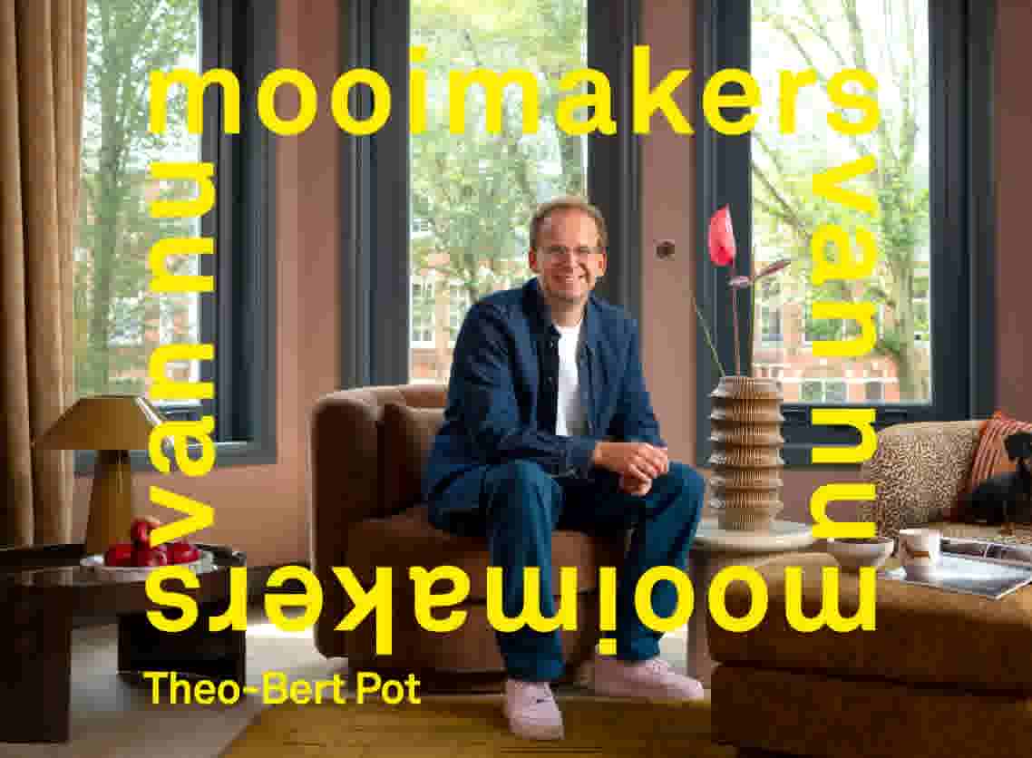Mooimakers van nu. Theo-Bert Pot. Theo-Bert Pot in spijkeroverhemd en spijkerbroek, zittend op een bruine fauteuil in een woonkamer met vaas en bloemen, een luipaardprint bank met hond, voor grote ramen.