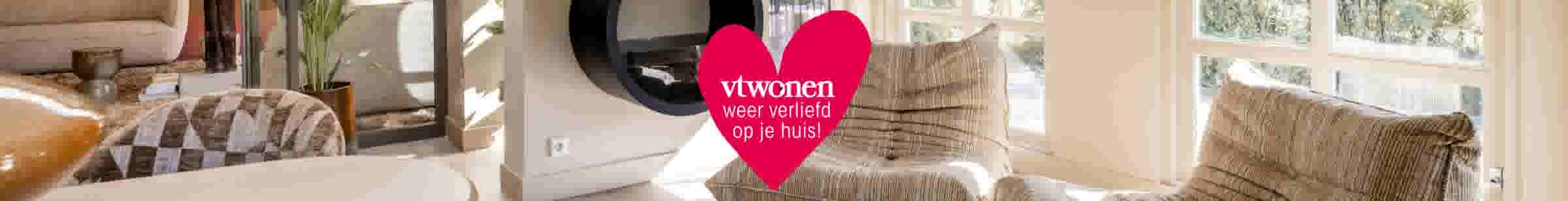 Lichte woonkamer met beige bank, moderne open haard en groot rood hart met tekst 'vtwonen weer verliefd op je huis!'