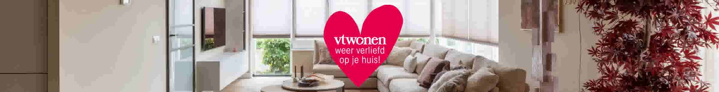 Moderne woonkamer met beige bank, houten salontafel en groot rood hart met tekst 'vtwonen weer verliefd op je huis!'