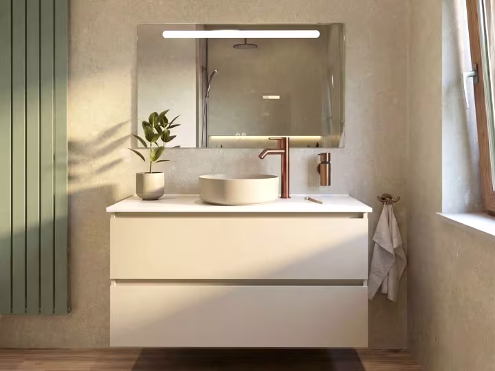 Moderne badkamer met witte wastafel, koperen kraan, groene radiator en kleine plant in pot op het meubel.