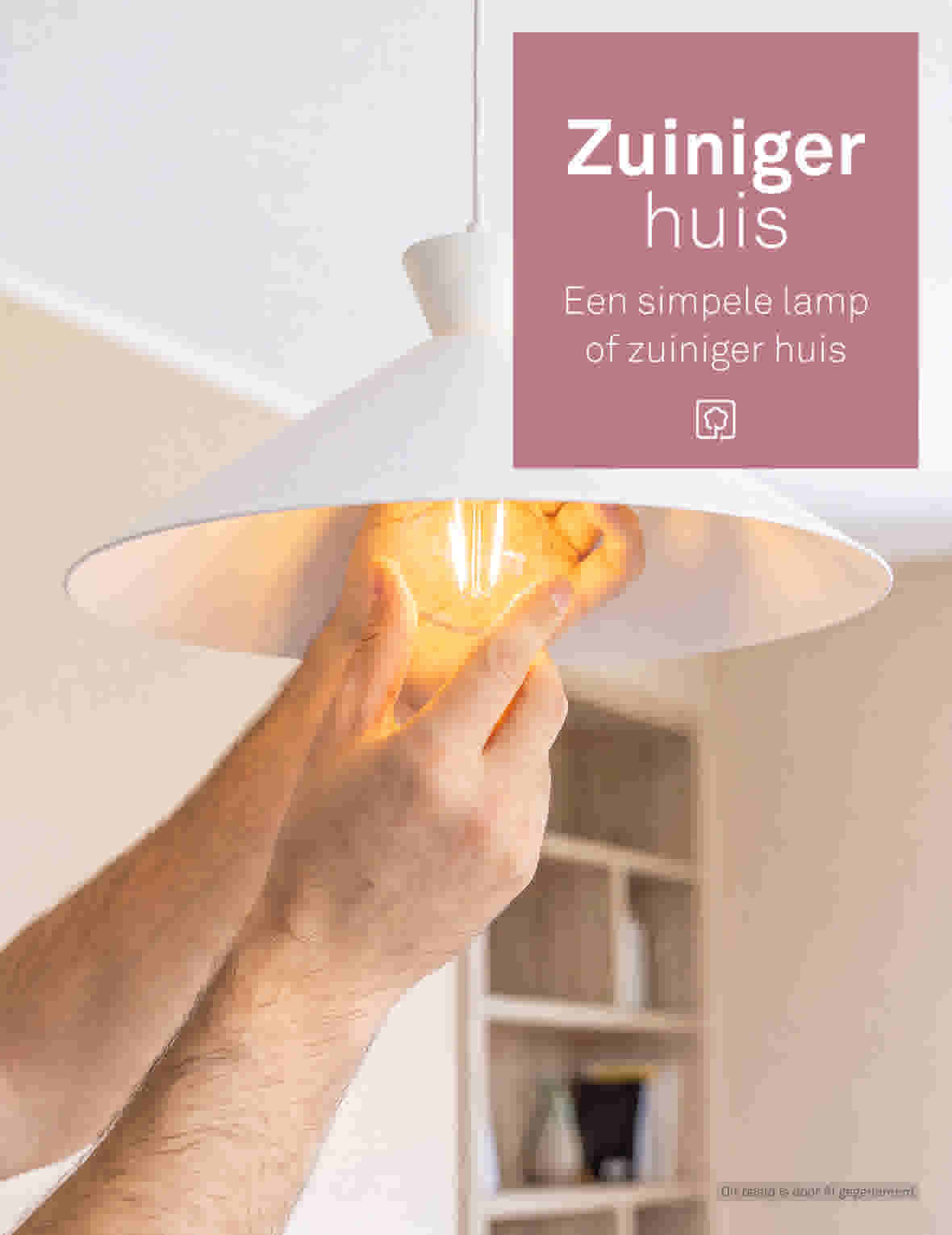 Hand die een gloeiende gloeilamp in een witte hanglamp plaatst met roze tekstbord 'Zuiniger huis' op achtergrond.