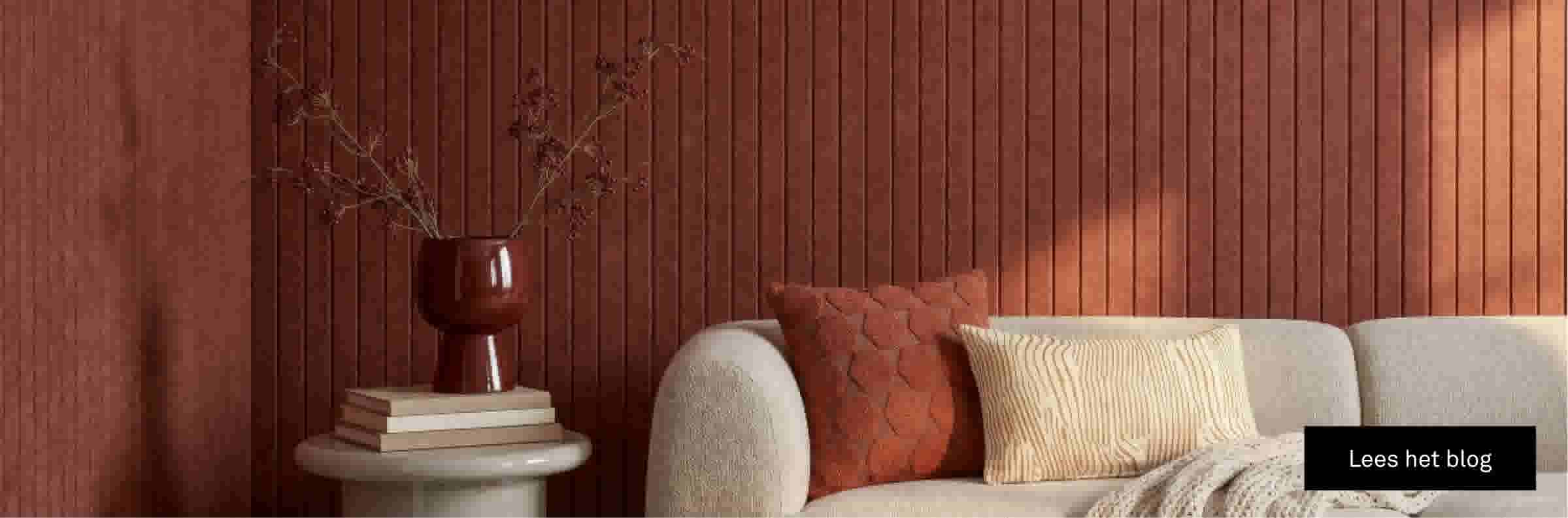Moderne woonkamer met beige bank, terracotta wandpanelen, decoratieve vaas en kussens in warme tinten.