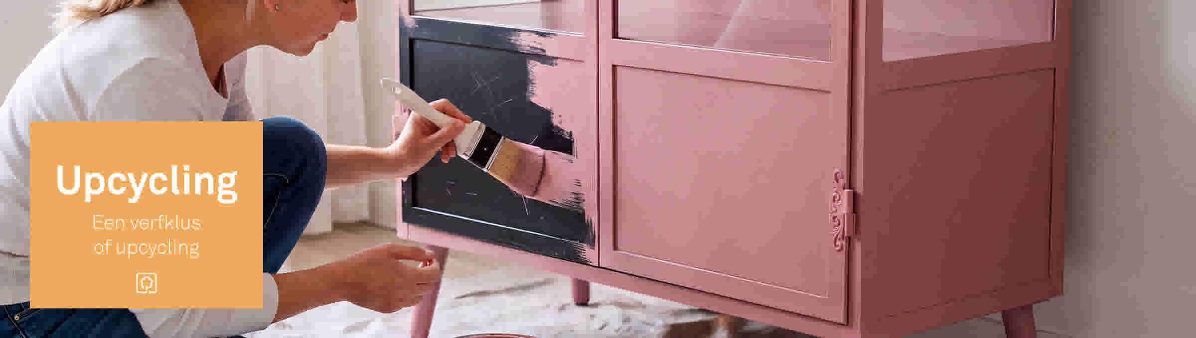 Vrouw schildert een roze kast met een kwast, met oranje tekstvak 'Upcycling - Een verfklus of upcycling'