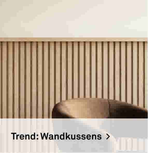 Trend: Wandkussens. Sfeerbeeld van een houten lamellenwand met een gestoffeerde stoel ervoor