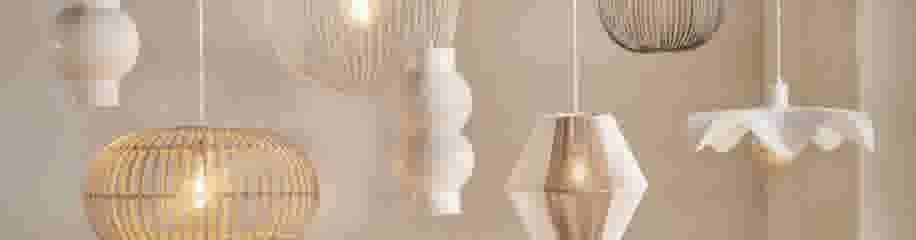 Zeven hangende lampen in verschillende stijlen en materialen, waaronder rotan, metaal en keramiek, in tinten wit en beige.