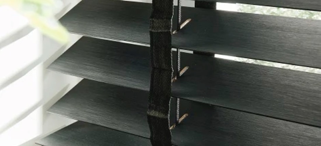 Zwarte jaloezieen hangend voor een raam