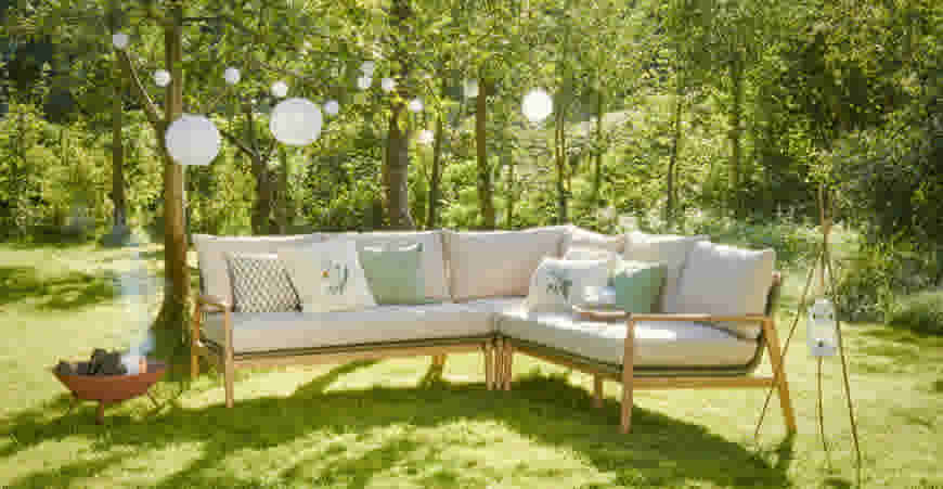 Lichtsnoeren in de tuin met witte lampionnetjes hangend boven een tuin loungeset met sierkussens